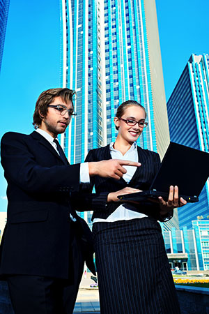 Businessman and businesswoman outside with a laptop
